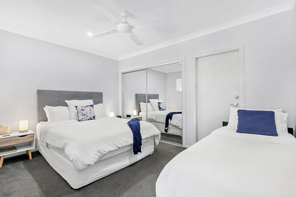 东梅特兰Mala Retreat, Shiraz Suite 5 Star Immaculate and Comfortable的一间白色卧室,配有两张床和镜子