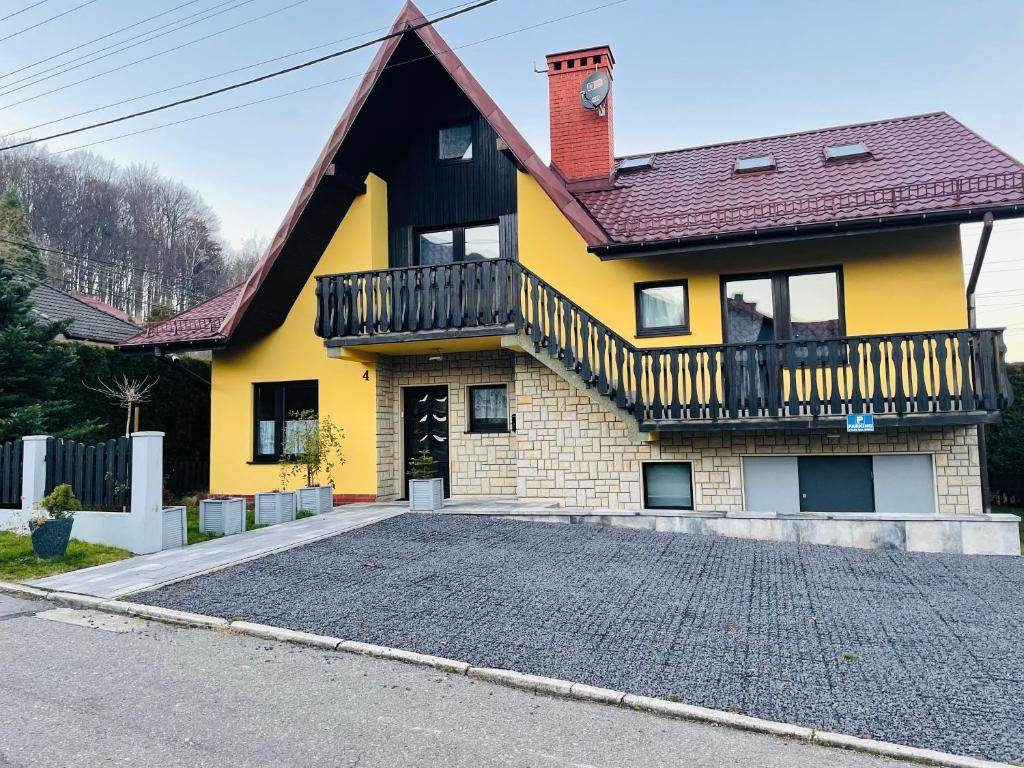 乌斯特龙Domek pod Czantorią的带阳台和车道的黄色房屋