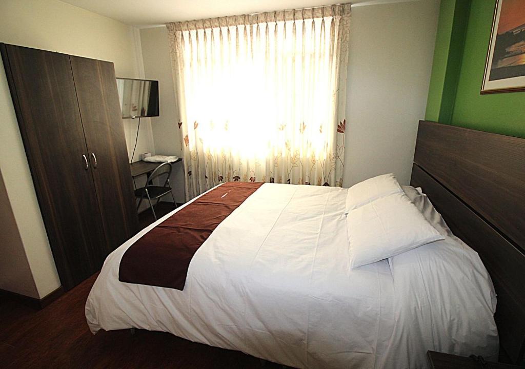 伊洛HOSTAL CORAL的卧室配有一张大白色床和窗户