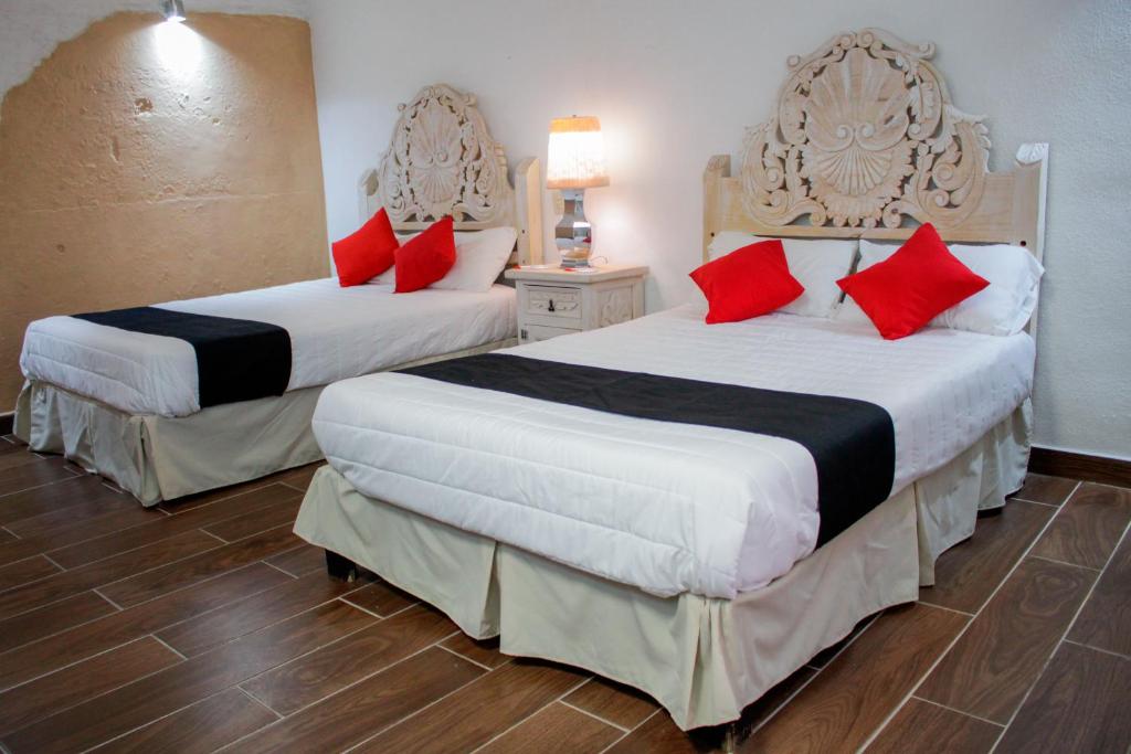 Apaseo el GrandeHotel Boutique Don Porfirio的两张位于酒店客房的床铺,配有红色枕头
