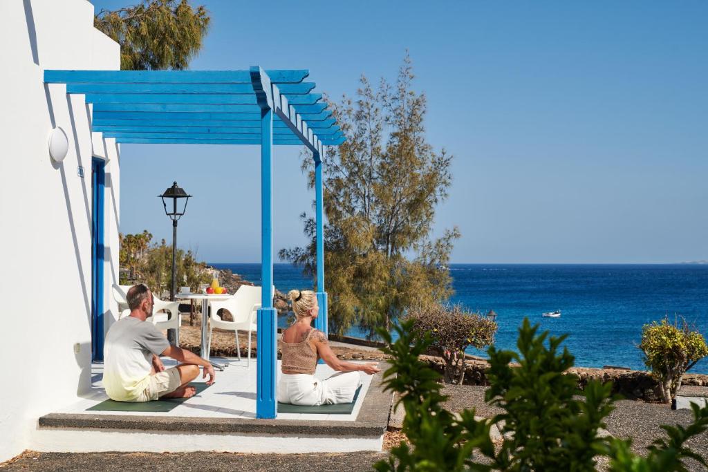 普拉亚布兰卡Sandos Atlantic Gardens的坐在俯瞰大海的凉亭中的男女