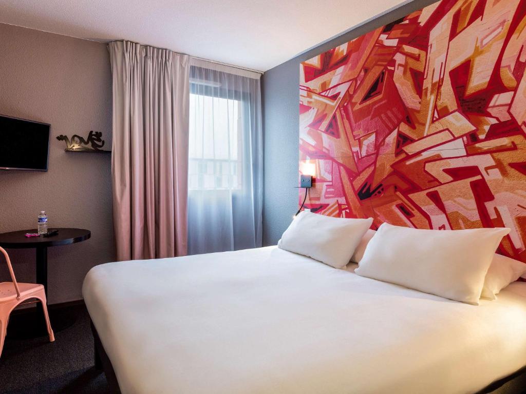 图卢兹Ibis Styles Toulouse Centre Canal du Midi的酒店客房设有一张白色大床,墙上挂有绘画作品