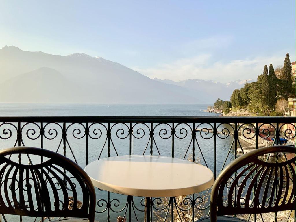 瓦伦纳Divina Vita Apartments的俯瞰水面的阳台配有一张桌子和两把椅子