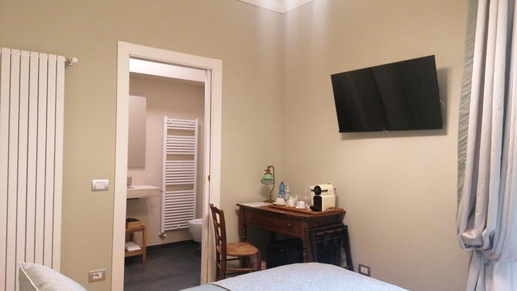 科莫Al Molo di Sant'Agostino的卧室配有书桌和墙上的电视。