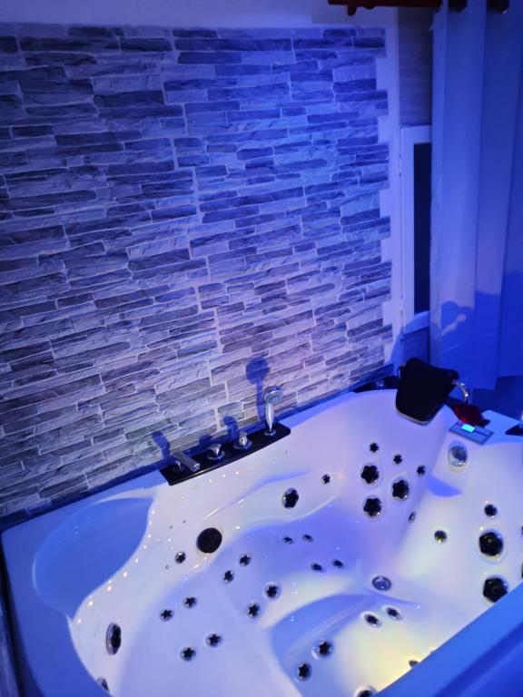 AmblainvilleDÉPENDANCE EN CHAMBRE D'HÔTE AVEC JACUZZI PRIVATIF DANS LA CHAMBRE v的砖墙客房内的浴缸