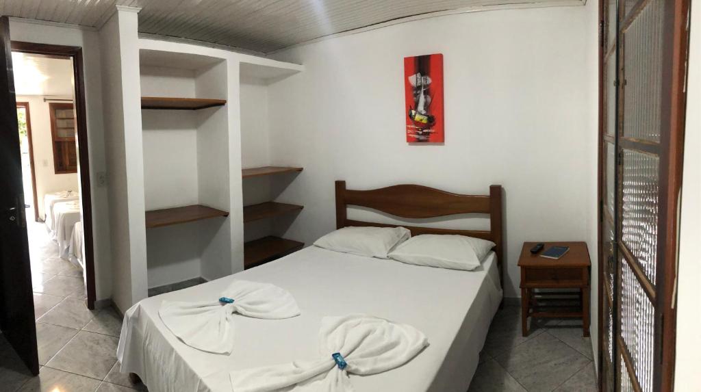 乌巴图巴Hotel Pousada Nosso Cantinho的一间小卧室,配有白色的床和一张桌子