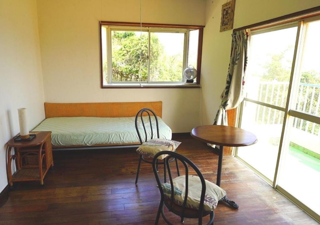 西之表市Ikokujyoucho - Vacation STAY 97595v的卧室配有一张床和一张桌子及椅子