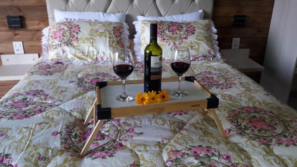 乌鲁佩马Pousada Sitio Bella Vista的床上有一瓶葡萄酒和两杯酒