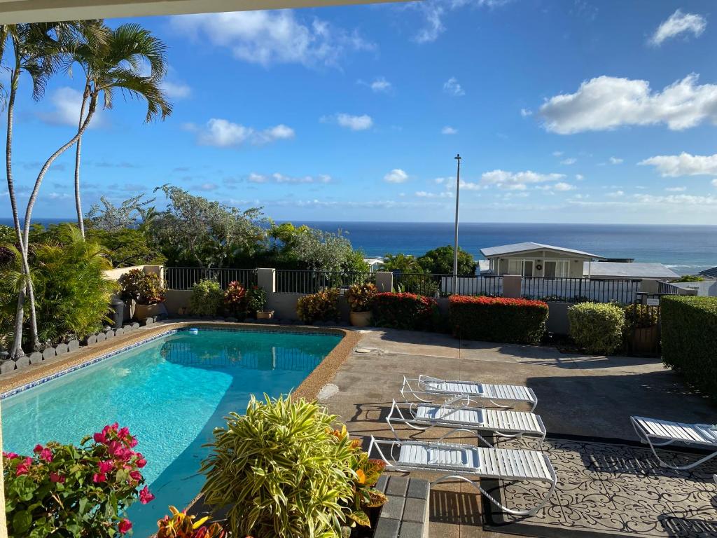 檀香山Paradise at Ehupua的一个带椅子的游泳池,背景是大海