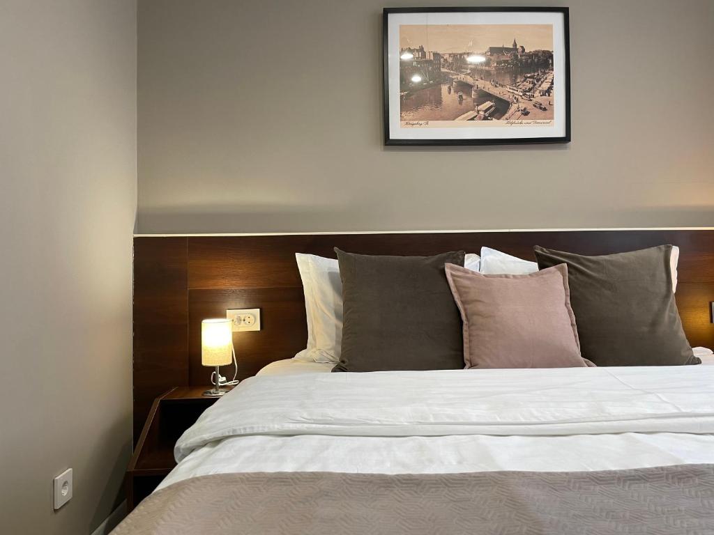 加里宁格勒卡利纳宾馆的卧室配有一张大床,墙上挂着一幅画