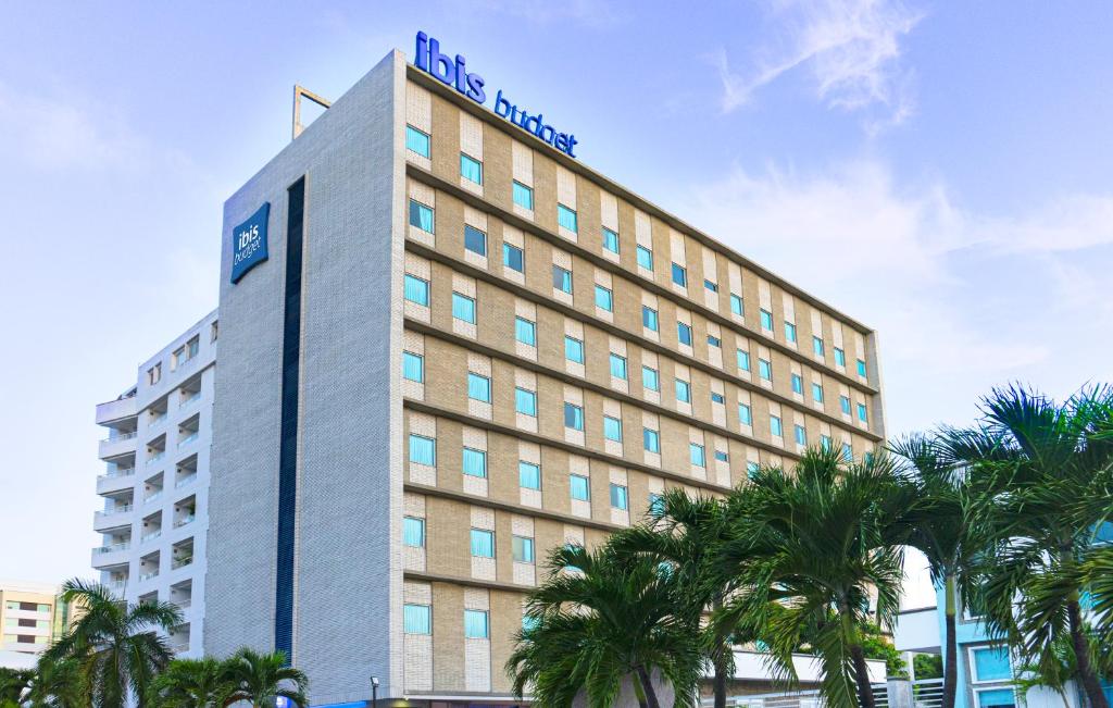 巴兰基亚ibis budget Barranquilla的一座酒店大楼前面有棕榈树