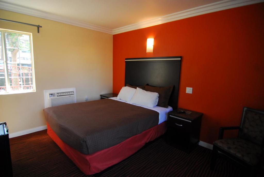 洛杉矶Studio City Inn - Near Universal Studios Hollywood的酒店客房,设有床铺和橙色墙壁
