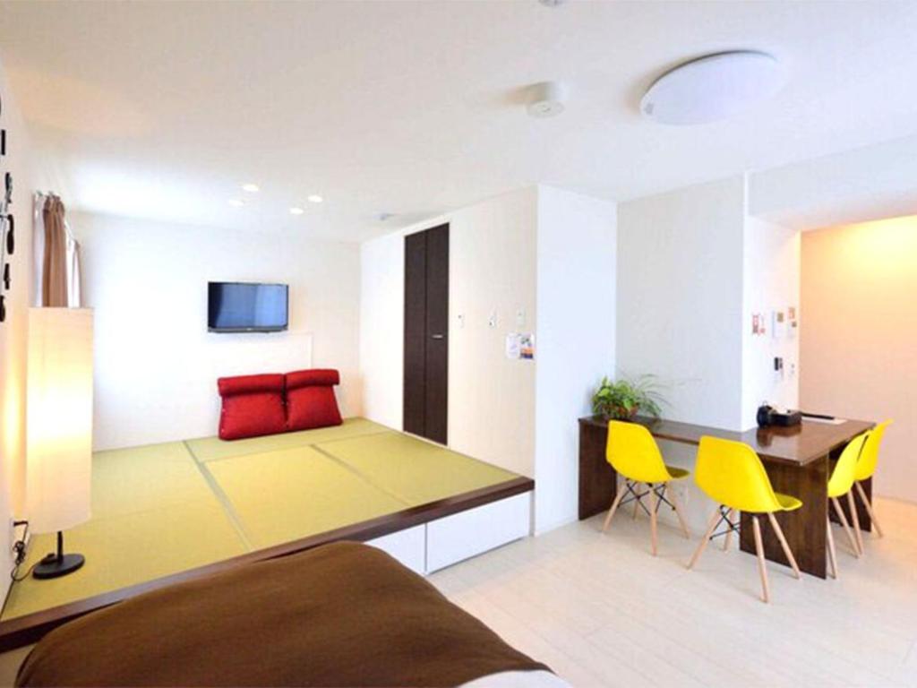 端岛Guest House Gifuhashima COCONE / Vacation STAY 33938的客房设有床、桌子和黄色椅子。