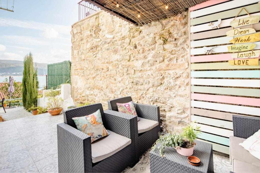 科尔库维翁El Mar en Lola Vistas al mar terrazas y jardín的一个带柳条椅和石墙的庭院