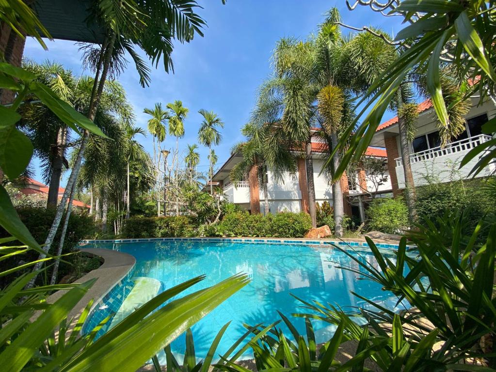 坤西育府Thara Cholapruek Resort - SHA Extra Plus的棕榈树屋前的游泳池