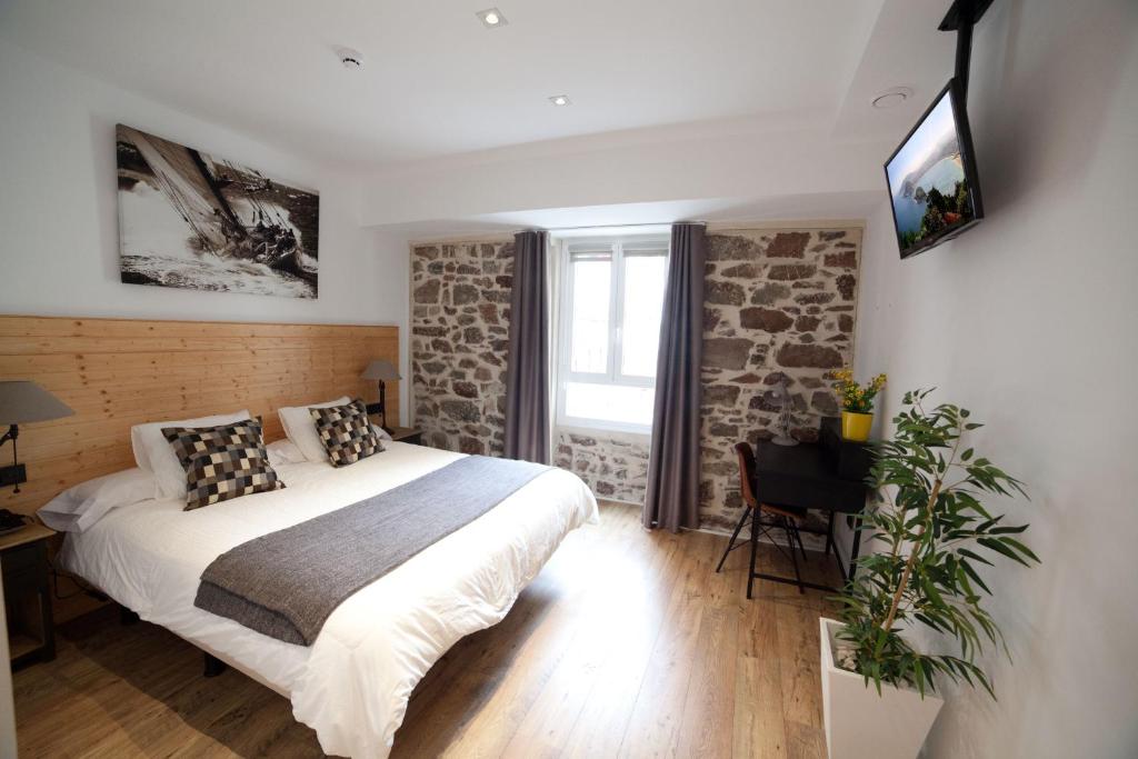 圣塞瓦斯蒂安卡萨尼可拉萨旅馆的卧室配有一张床,墙上配有电视。