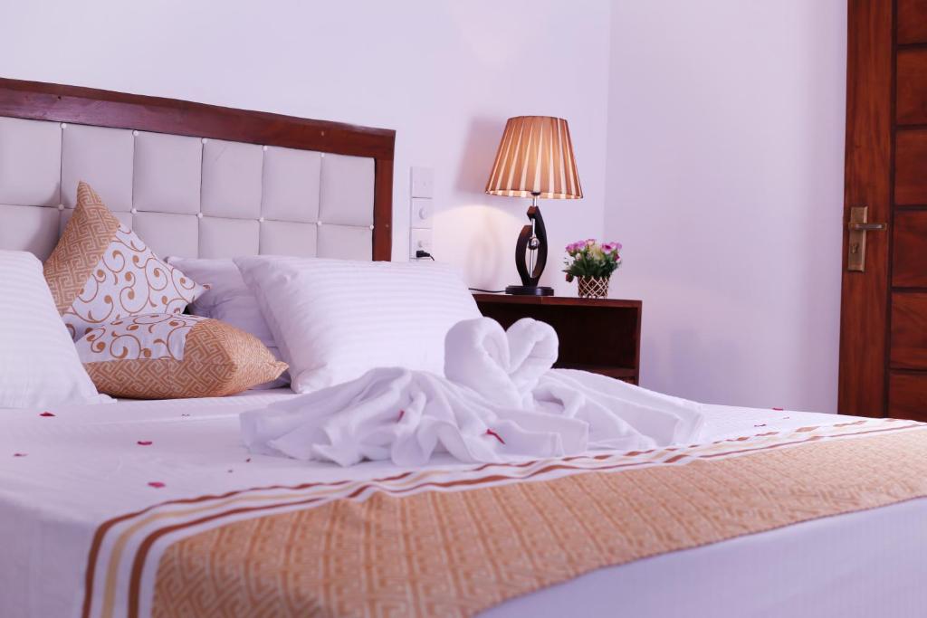 乌纳瓦图纳Triple Edge Villa的卧室配有白色的床,上面有弓