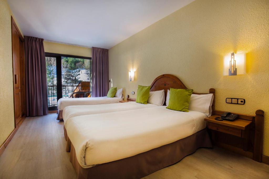 阿林萨尔Hotel Sant Gothard的配有绿色枕头的酒店客房内的两张床