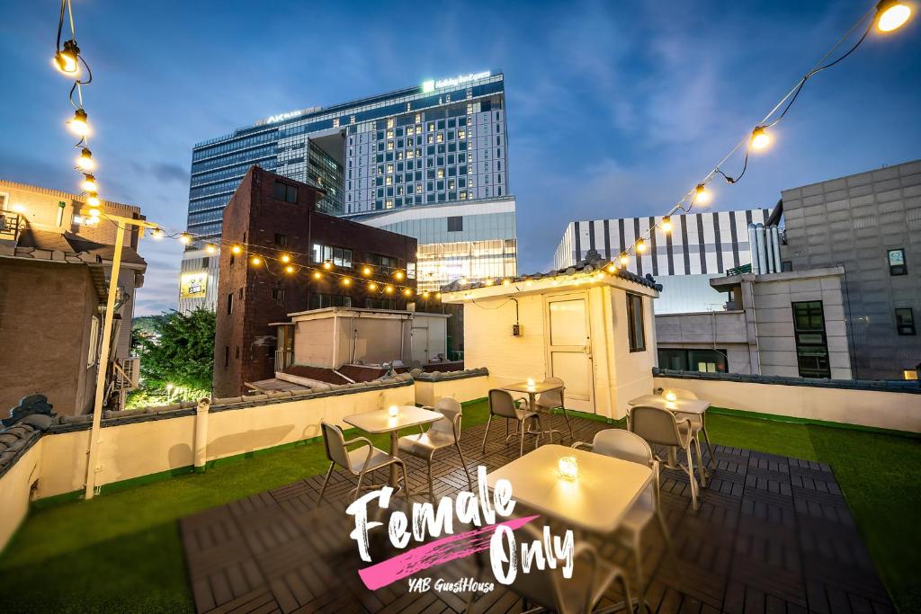 首尔YAB-GuestHouse, FemaleOnly, ForeignOnly的屋顶露台配有桌椅和灯光