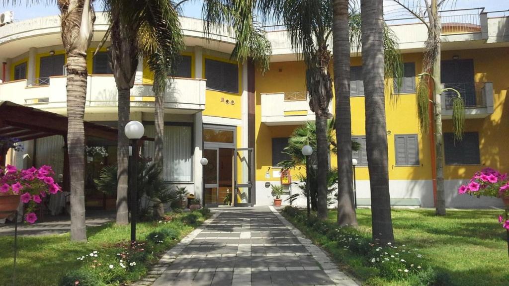 马斯卡利Oasi Park Hotel的棕榈树和走道的黄色建筑