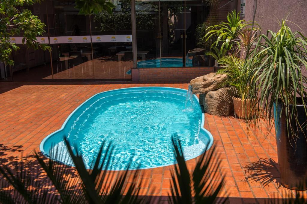 伊瓜苏Pousada Nanai的种植了植物的庭院里的一个蓝色游泳池