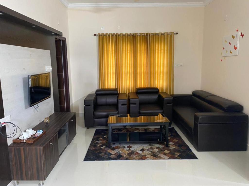 蒂鲁帕蒂OM SRINIVASA - TRULY HOMESTAY的客厅配有黑色真皮沙发和桌子