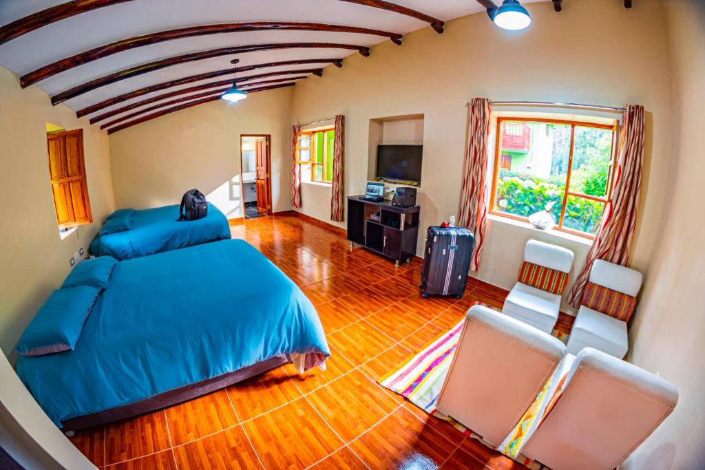 乌鲁班巴Happy Land Valle Sagrado的一间卧室配有蓝色的床和两把椅子