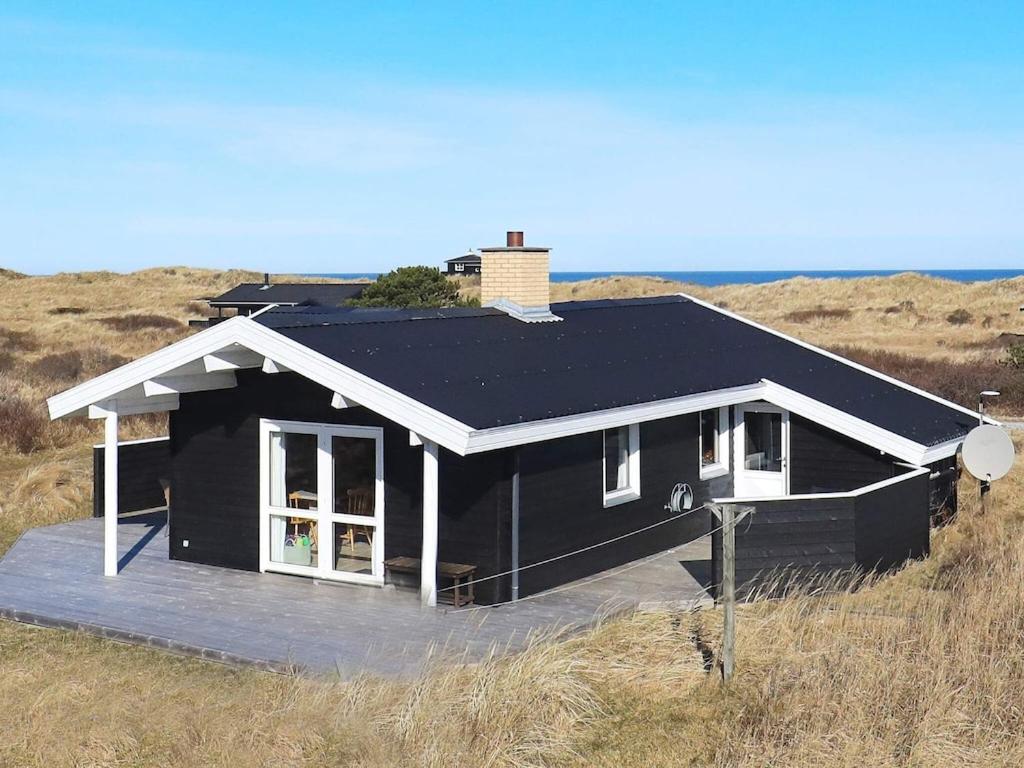 希茨海尔斯Three-Bedroom Holiday home in Hirtshals 4的田野中间的黑房子