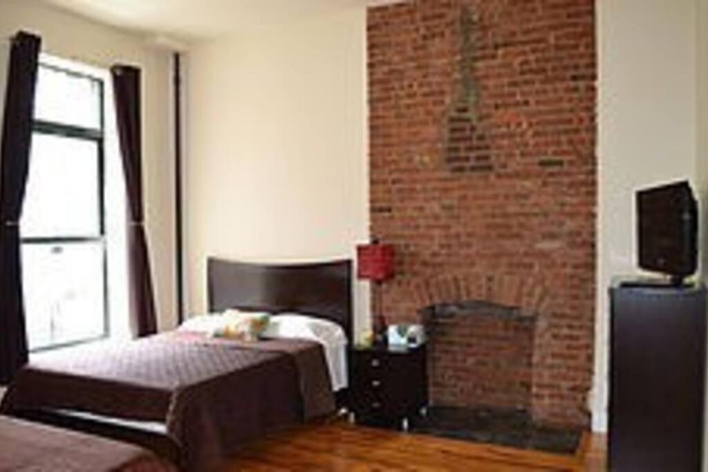 纽约136TH UNIT 1的一间卧室设有一张床和砖墙