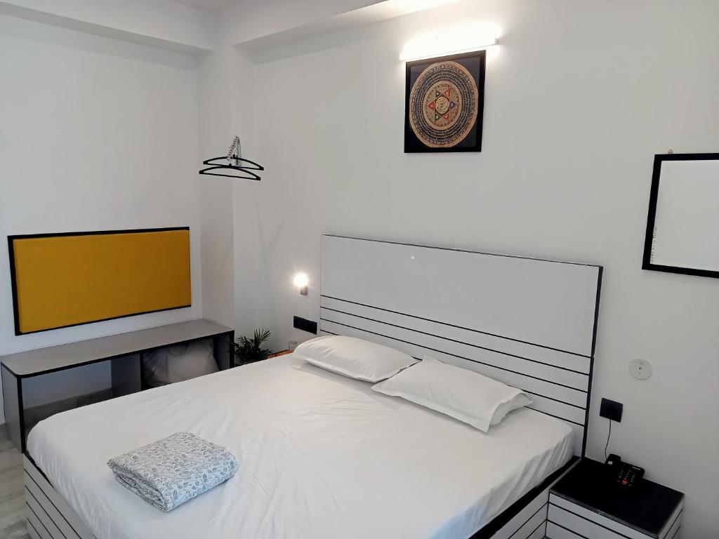 斋浦尔Divy Villa的卧室配有白色的床和平面电视。