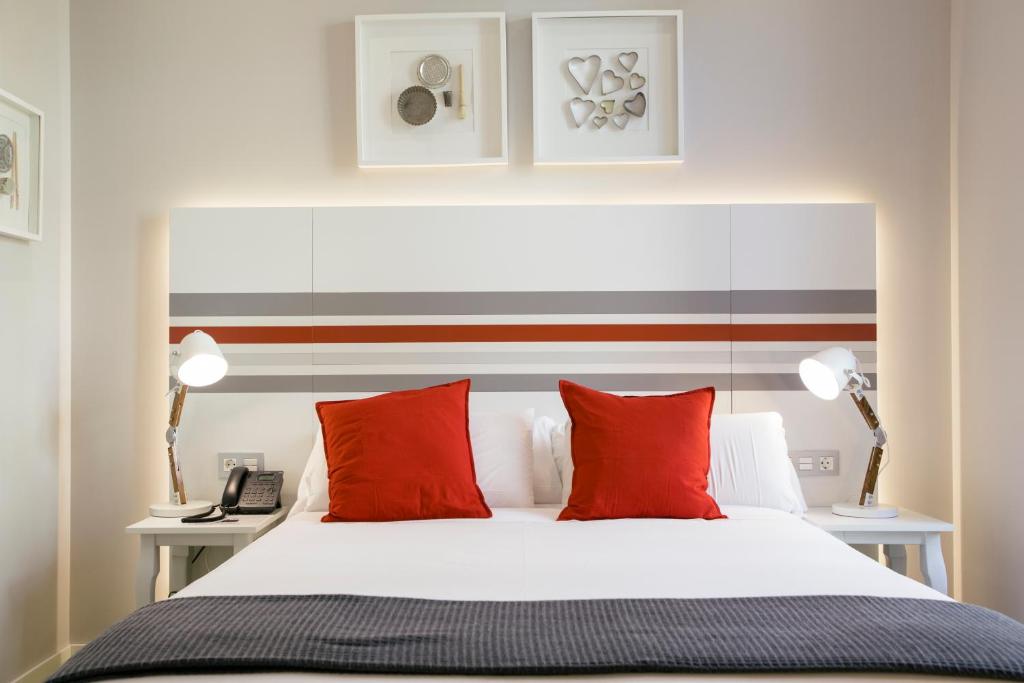 圣塞瓦斯蒂安Legazpi Doce Rooms & Suites的卧室配有带红色枕头的白色床
