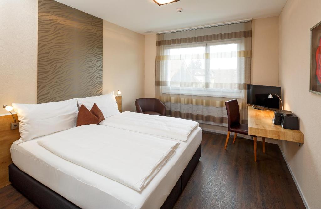 Villmergen维尔摩根瑞士品质酒店的酒店客房设有一张大床和一张书桌。