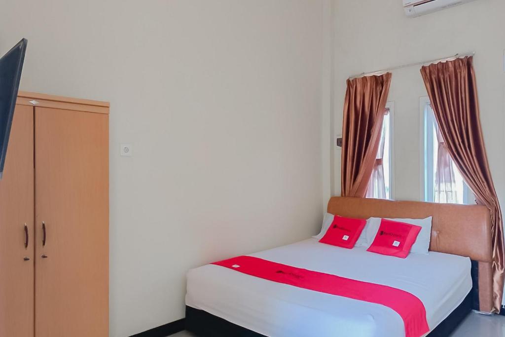 巴厘巴板RedDoorz At Pelangi Guest House的一间卧室配有带粉红色枕头的床和窗户。