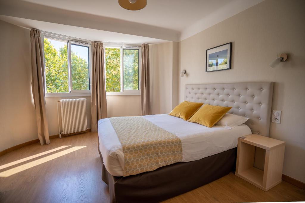 佩皮尼昂蒙蒂阿尔酒店的一间卧室设有一张大床和两个窗户。