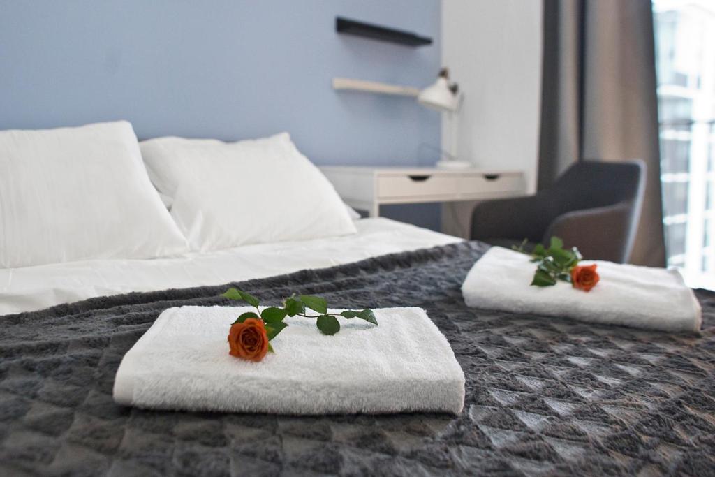 华沙zoliborz的酒店客房的床上配有2条毛巾和玫瑰花