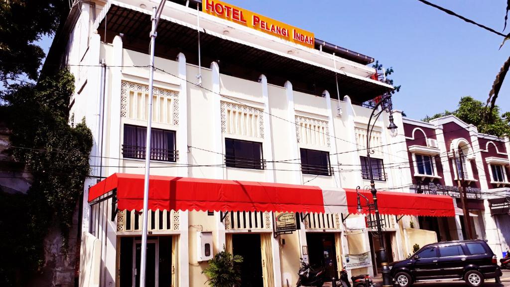 三宝垄Hotel Pelangi Indah的一条白色的建筑,在街上有红色遮阳篷