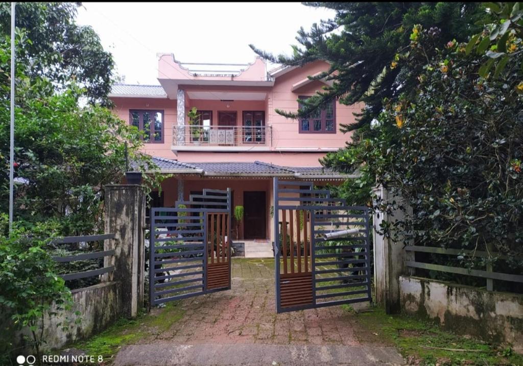 玛纳多迪Puzhayoram home stay, Palakkuli, Mananthavadi wayanad kerala的粉红色的房子,设有大门和栅栏