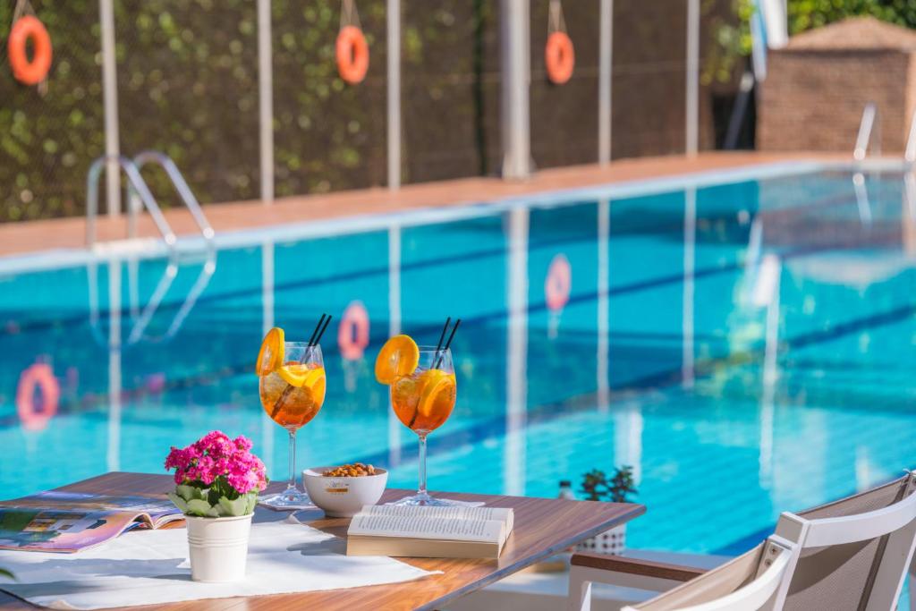 塞沃塔Sivota Hotel的游泳池旁带两杯酒的桌子