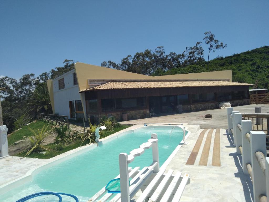 阿拉亚尔-杜卡布Hotel fazenda Pousada Fazendinha beach club arraial do cabo的一座带椅子的游泳池以及一座建筑