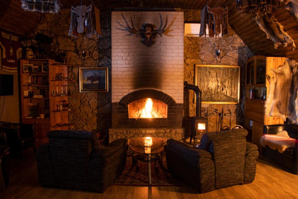 (( Šarlote ))Hunter's Lodge的客厅设有壁炉、两把椅子和一张桌子