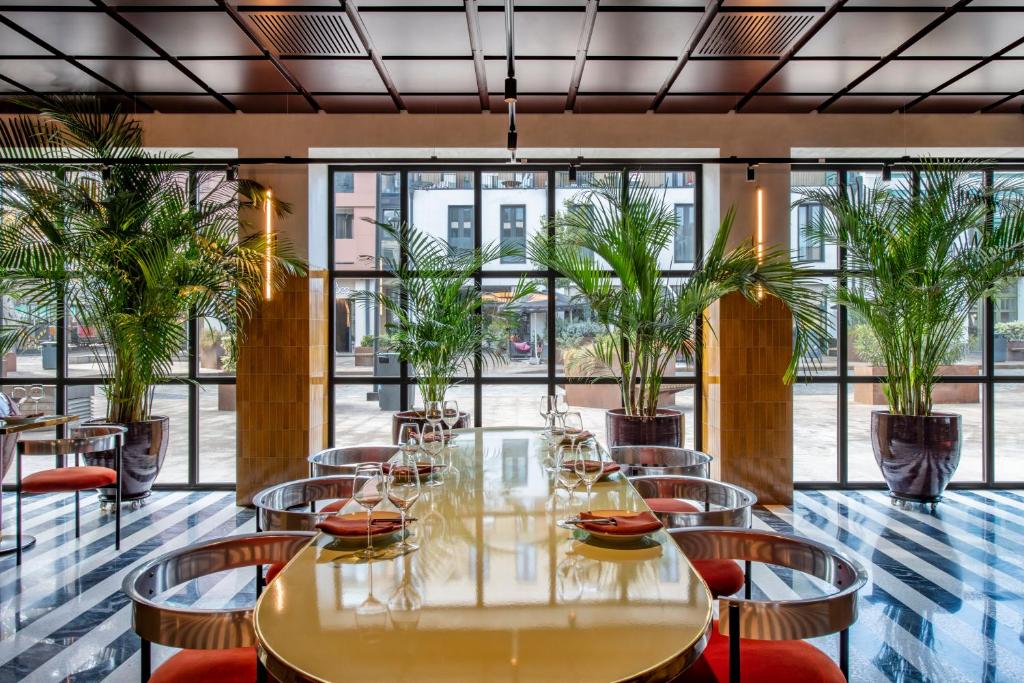 第比利斯Bazzar Boutique Hotel的一间设有桌椅和棕榈树的餐厅