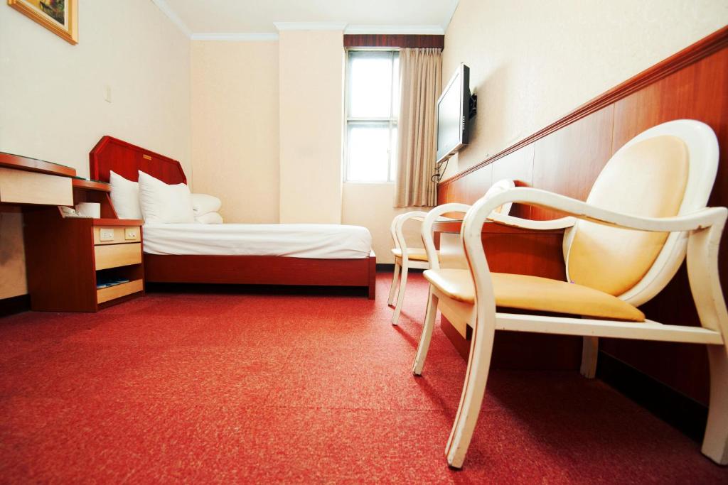 台北华达大饭店的酒店客房,配有两张床和椅子