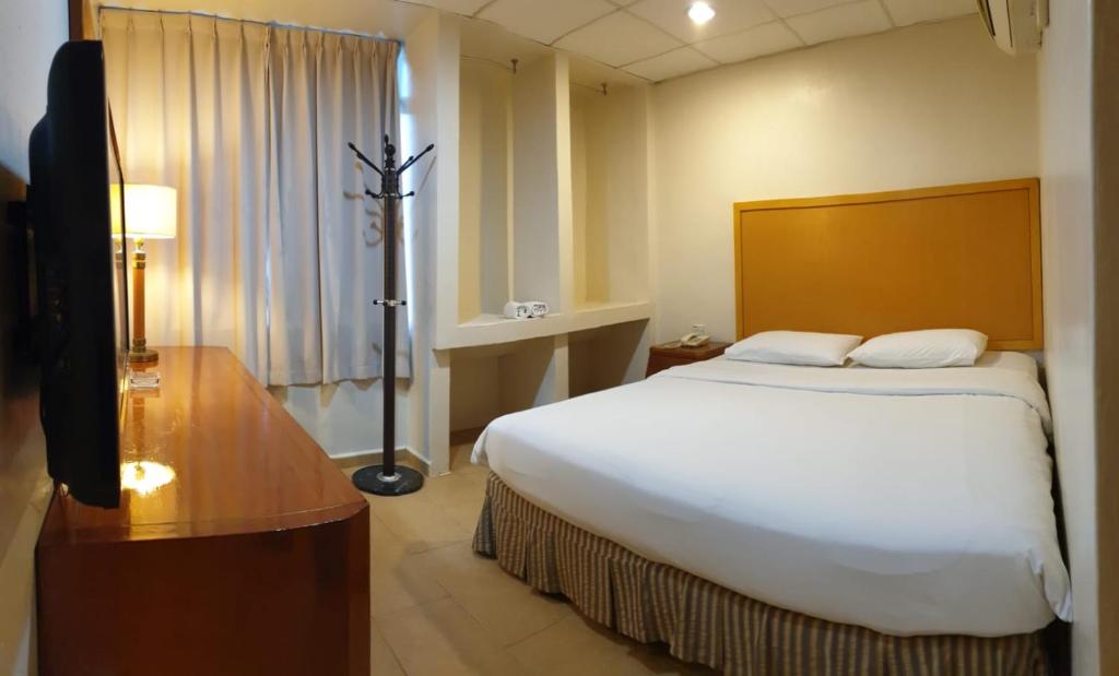 新山Golden Court Hotel - Sri Pelangi的酒店客房设有一张大床和一台电视。
