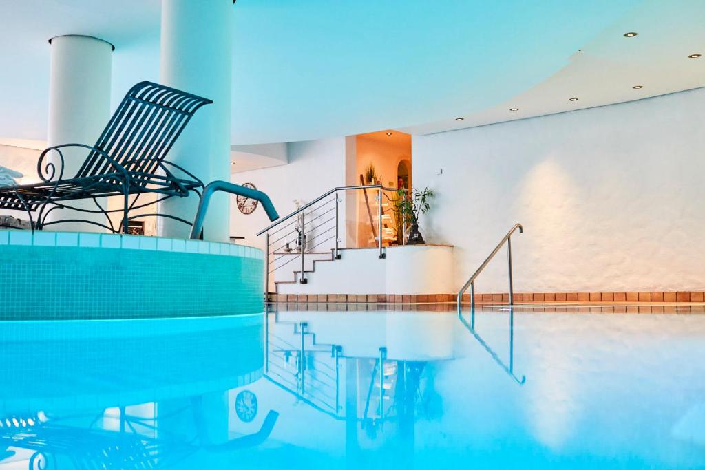 圣彼得奥尔丁杜塞尔多夫兰德豪斯酒店的一座带两把椅子的游泳池和一座房子内的楼梯