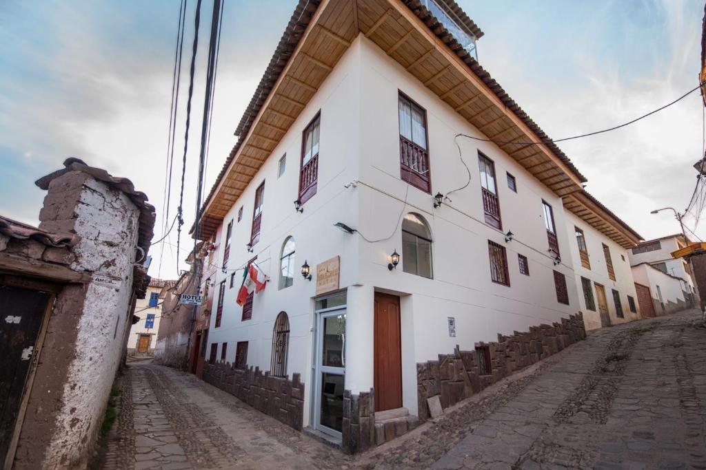 库斯科Hotel Luna de Oro Cusco的街道边的白色建筑