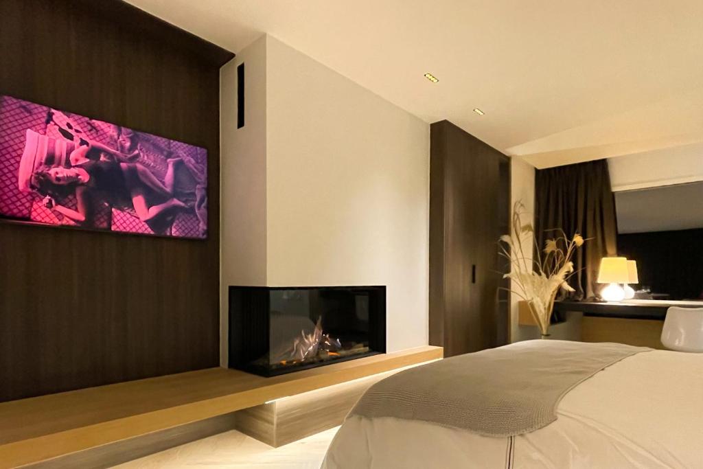 那慕尔Le19 Suite Georges & Lucy的卧室设有壁炉和墙上的电视。