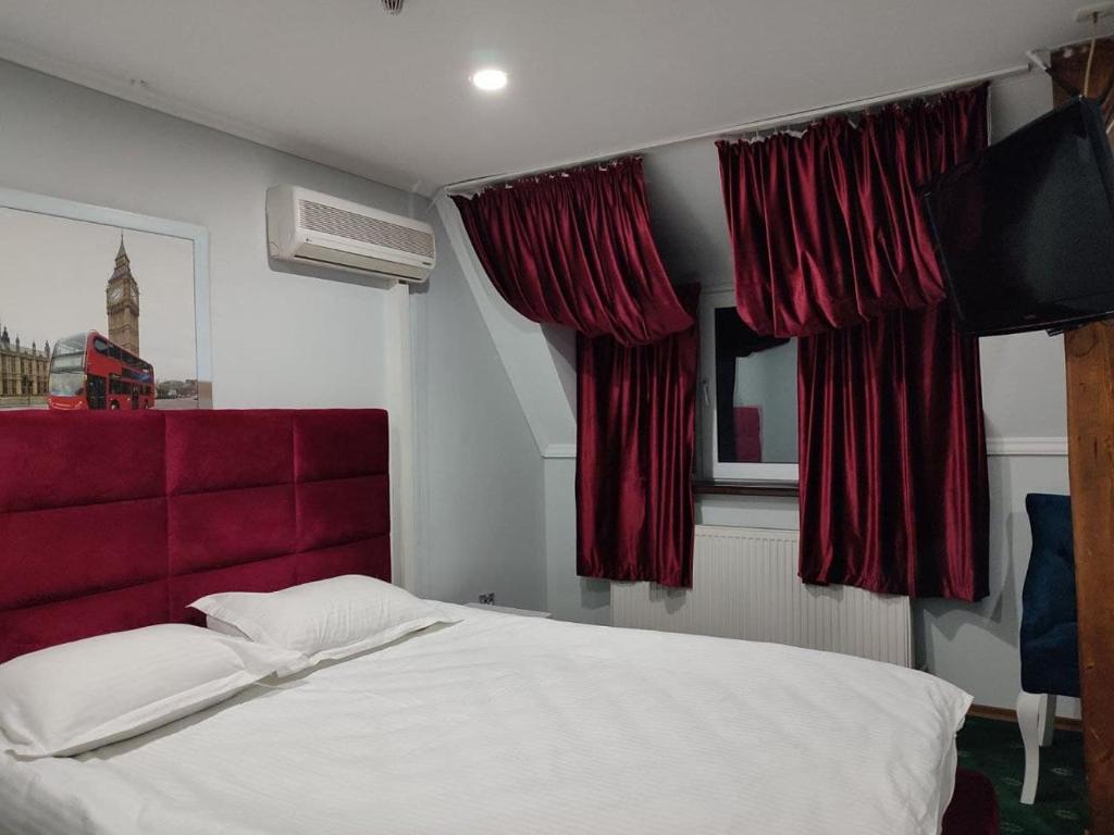切尔诺夫策Leoton Chernivtsi的一间卧室配有一张带红色床头板和窗帘的床