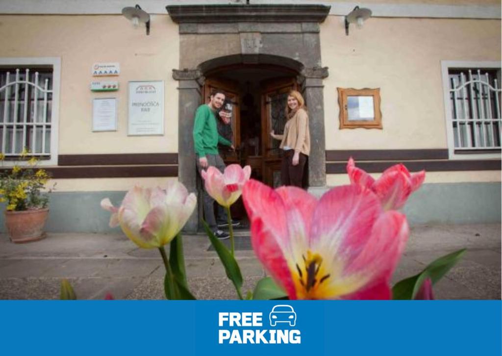 卡姆尼克波德斯卡卢住宿加早餐酒店的站在一座粉红色花朵的建筑外的男人和女人