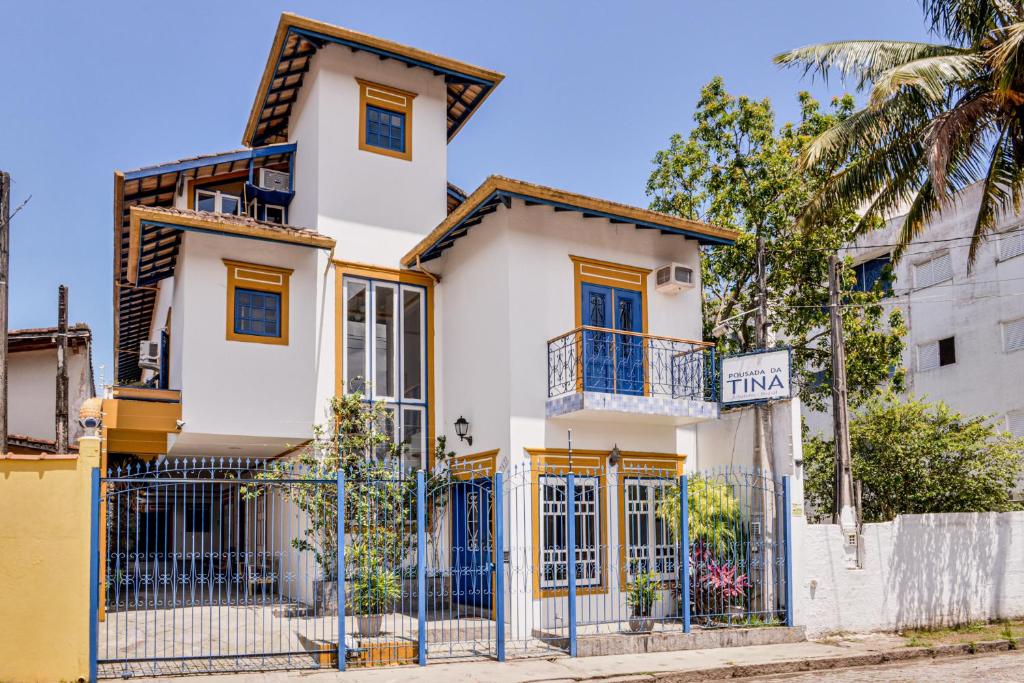 乌巴图巴Pousada da Tina的白色的房子,设有蓝色的窗户和栅栏