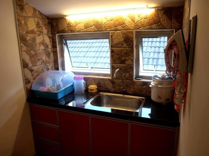 亚依淡房租名概念旅馆的带水槽的厨房台面和2扇窗户